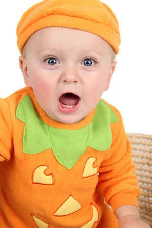 Baby dressed in a pumpkin costume on white backgroundの写真素材