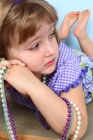 Cutle little girl lying, resting her cheek on her handsの写真素材