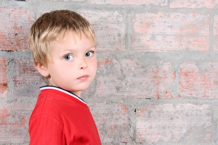 Cute toddler boy against a brick wall backgroundの写真素材