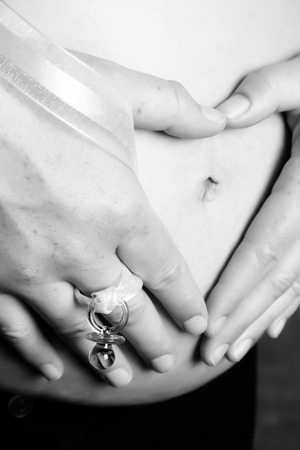 Pregnant woman holding her belly making a heart shapeの写真素材