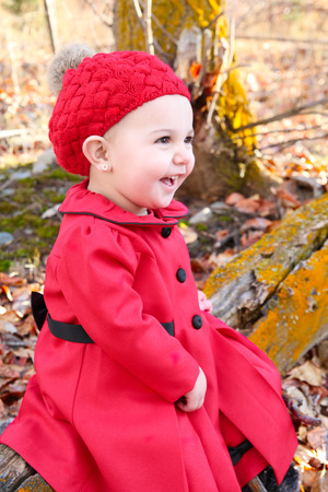 Little girl wearing a red coat and hat in the forestの写真素材
