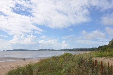 nice beach scene with a blue sky and two people walking in swansea in welshの写真素材