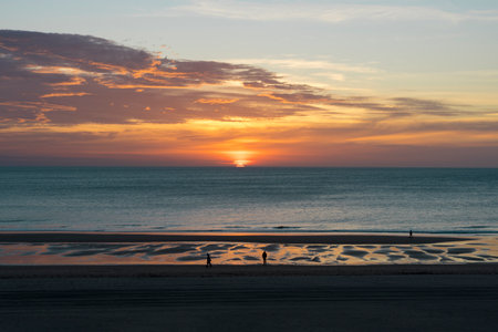wonderful and colorful sunset on the beach with the silhouette of peopleの写真素材