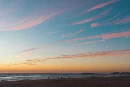 wonderful and colorful sunset on the beach with the silhouette of peopleの写真素材