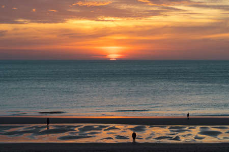 wonderful and colorful sunset on the beach with the silhouette of peopleの写真素材