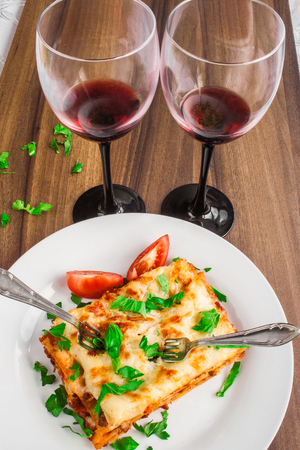 Dinner for two. Italian lasagna bolognese and red wine.の写真素材