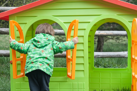 Looking for home! Small kid looking through the window of a plastic house.の写真素材