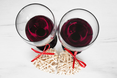 Romantic gesture - Close up image of two glasses with red wine with heart decoration.の写真素材