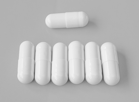White pills on grey background.