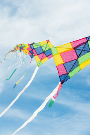 Colorful long line kites flying in blue skyの写真素材