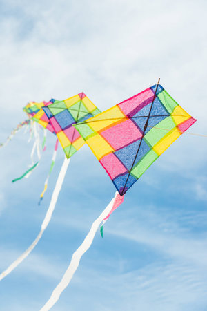 Colorful long line kites flying in blue skyの写真素材
