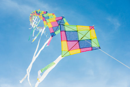 Colorful long line kites flying in blue skyの写真素材
