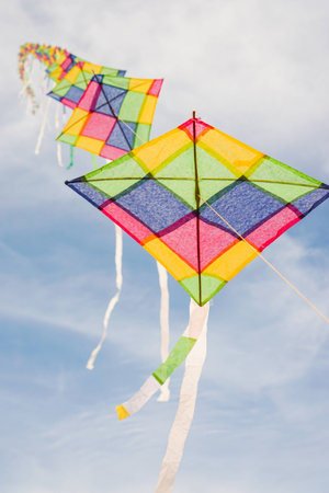Colorful long line kites flying in blue skyの写真素材