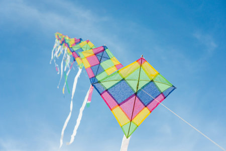 Colorful long line kites flying in blue skyの写真素材