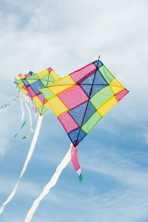 Colorful long line kites flying in blue skyの写真素材