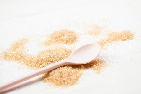 Close up of sugar and empty spoon on white background.の写真素材