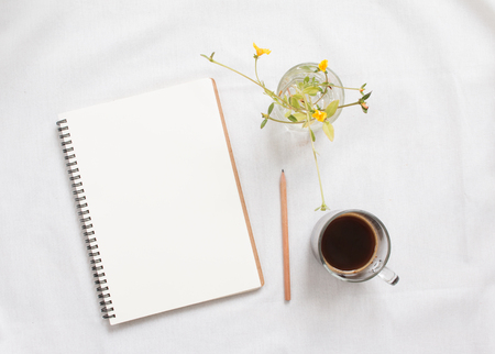 Top view of blank notebook and flower on white workspace background.の写真素材