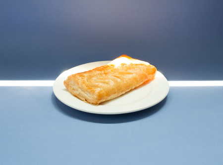 Homemade Corn Pie on white plate on blue background. Sunshine from the window.の写真素材