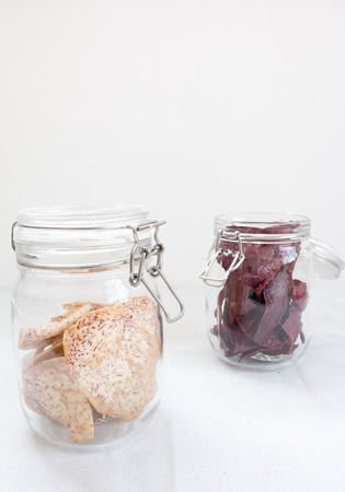 Crisp Fried Taro and sweet potato in glass jar on white  backgroundの写真素材