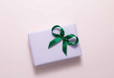 Top view of pastel gift with green bow box on pink background.の写真素材