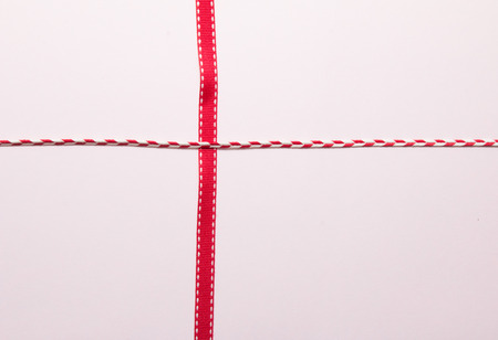 Variety of red ribbons on soft pink paper background.の写真素材