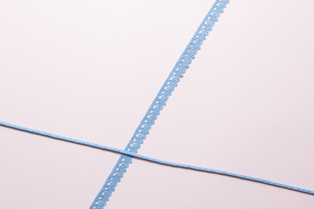 Blue ribbon on soft pink paper background.の写真素材