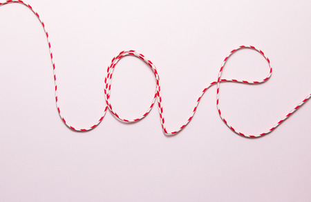 Red rope on soft pink paper background.の写真素材