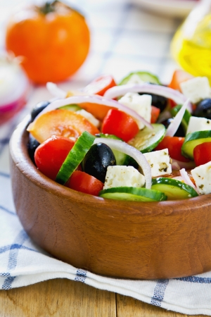 Greek salad in a wood bowl by fresh ingredientsの写真素材