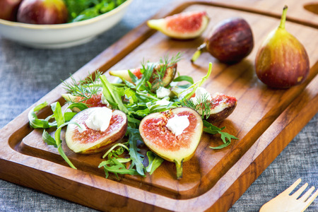 Fig with Goat cheese and Rocket salad on wooden chopping boardの写真素材