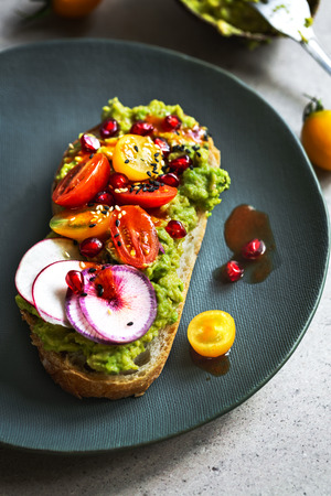 Mashed Avocado with Cherry Tomato, Radish,  Pomegranate, Sesame on toast with Chili sauceの写真素材