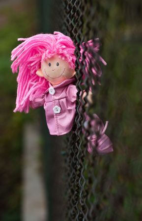 Pink doll on green fenceの写真素材
