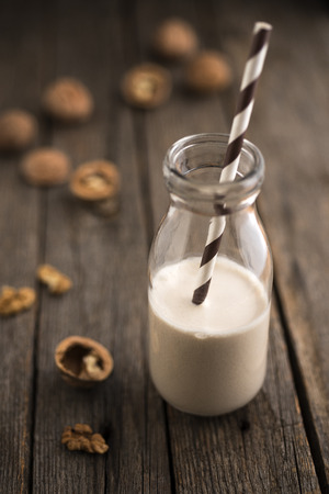 Nut milk with walnuts on wood tableの写真素材
