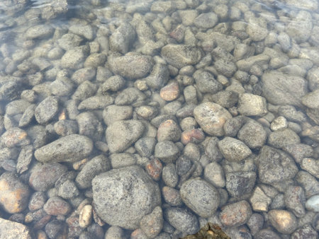 Water and stones in shallow river. Pebble bottom of lake.