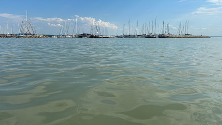 Lake with marina on skyline, beautiful summer landscape with water surface and cloudy sky.の写真素材
