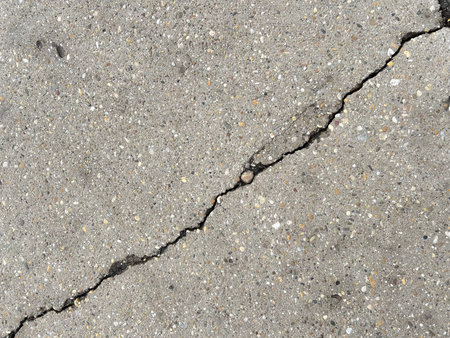 Horizontal picture of cracks smooth concrete surface. Single diagonal deep crevice.