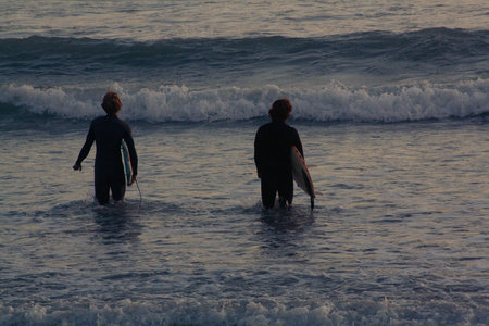 Surfers at sunset on the beach in San Diego, California