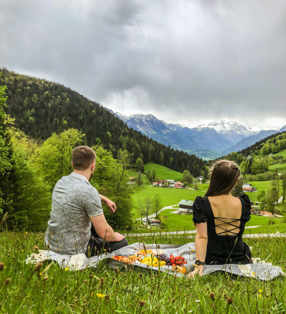 Couple sitting on a meadow in the mountains and having a picnicの写真素材