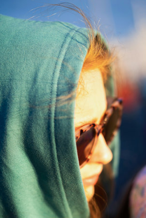 Portrait of a beautiful girl in sunglasses and a green hoodieの写真素材