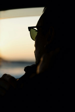 Silhouette of a man with sunglasses at sunset on the beachの写真素材