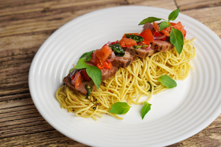 Spaghetti with tuna, tomatoes and basil on a white plate.の写真素材