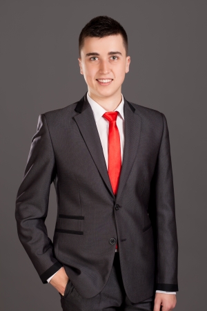 Young businessman standing on grey backgroundの写真素材