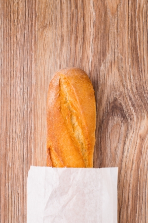 Baguette in paper bag on a wooden backgroundの写真素材