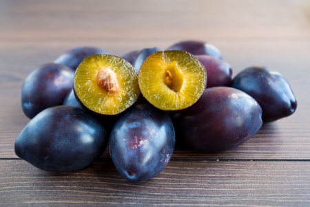 Many fresh ripe plums on wooden boardの写真素材