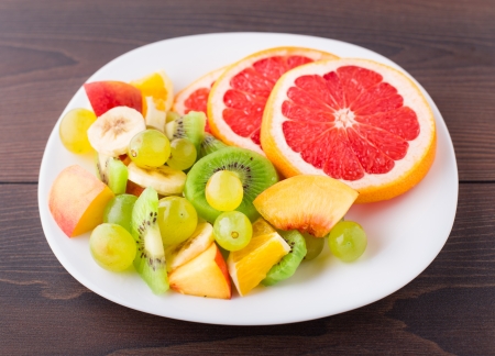 Assortment of sliced fruits on white plateの写真素材
