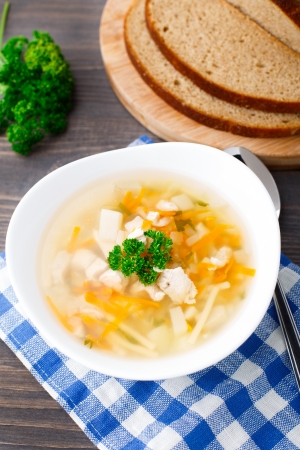 Bowl of chicken soup with vegetables and noodles on a blue napkinの写真素材
