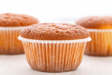 Three tasty muffin cakes on a wooden tableの写真素材