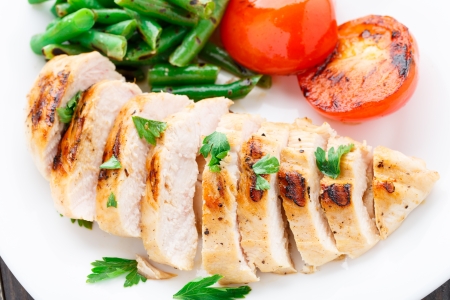 Grilled chicken with green beans and tomatoes on a plateの写真素材