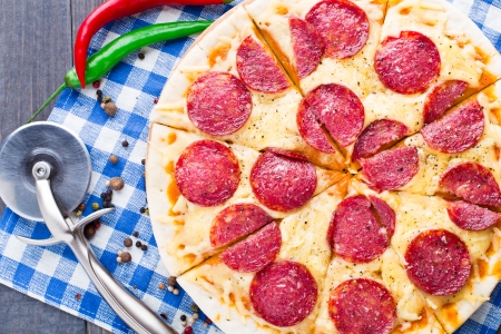 Freshly baked delicious pizza with salami on a blue napkinの写真素材