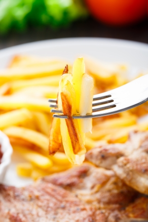 Delicious french fries on a fork. Fried meat with ketchup on a backgroundの写真素材
