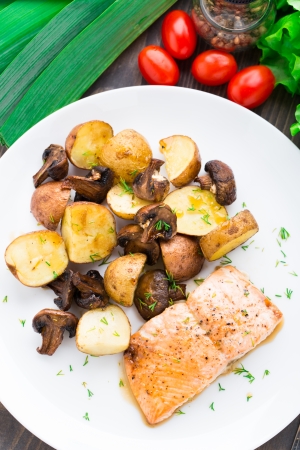 Roasted salmon with potatoes and mushrooms on a plateの写真素材